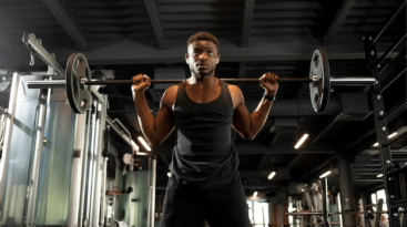 young-african-american-man-lifts-barbell-dark-gym-sports-guy-trains-fitness-room_164411-4087